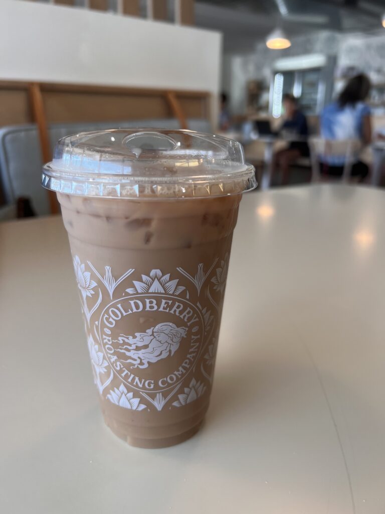 an iced latte in a clear cup sits on a table.